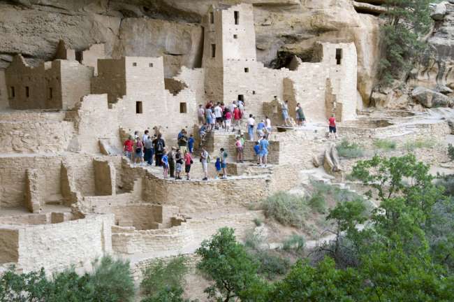 A group of tourists accompanied by a National Park Service guide tour the Cliff Palace ruins, Mesa Verde National Park, Colorado, USA
