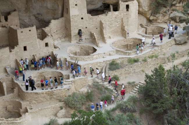 A group of tourists accompanied by a National Park Service guide tour the Cliff Palace ruins, Mesa Verde National Park, Colorado, USA