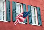 Charleston, South Carolina, USA.  An Amerian flag flies over windows on a colorful historic building in downtown Charleston.